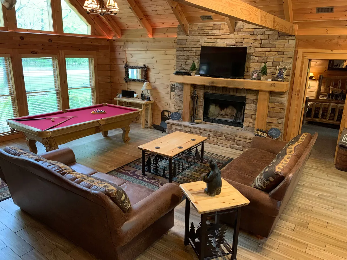 A cozy and inviting area featuring a pool table, rustic wooden furnishings, a welcoming fireplace, and large windows that let in natural light. The arrangement encourages both group interaction and moments of relaxation, with clear sightlines between activity zones.