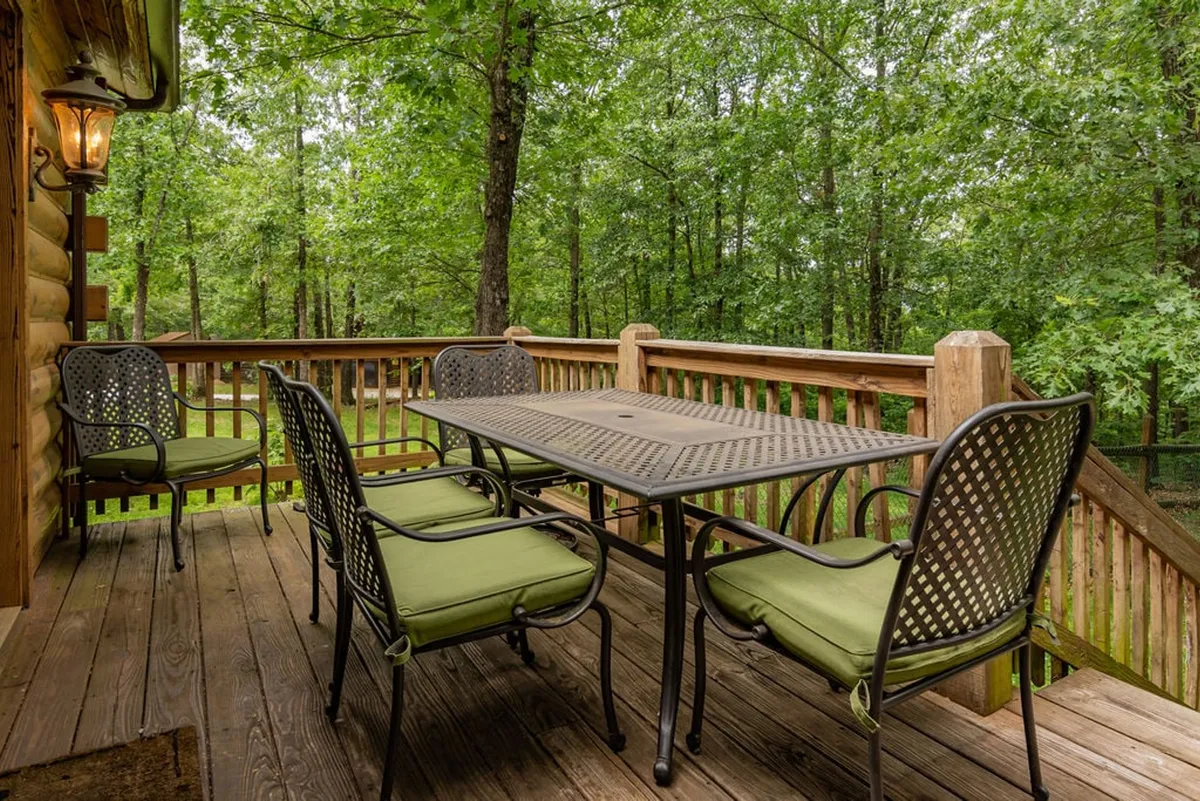 This image presents an inviting outdoor dining area with a table and comfortable seating set amid greenery. The scenery suggests alfresco meals and socializing in a peaceful wooded setting.